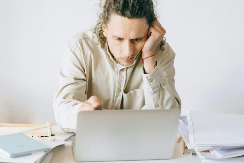 Man with a confused look on his face while looking down at his laptop