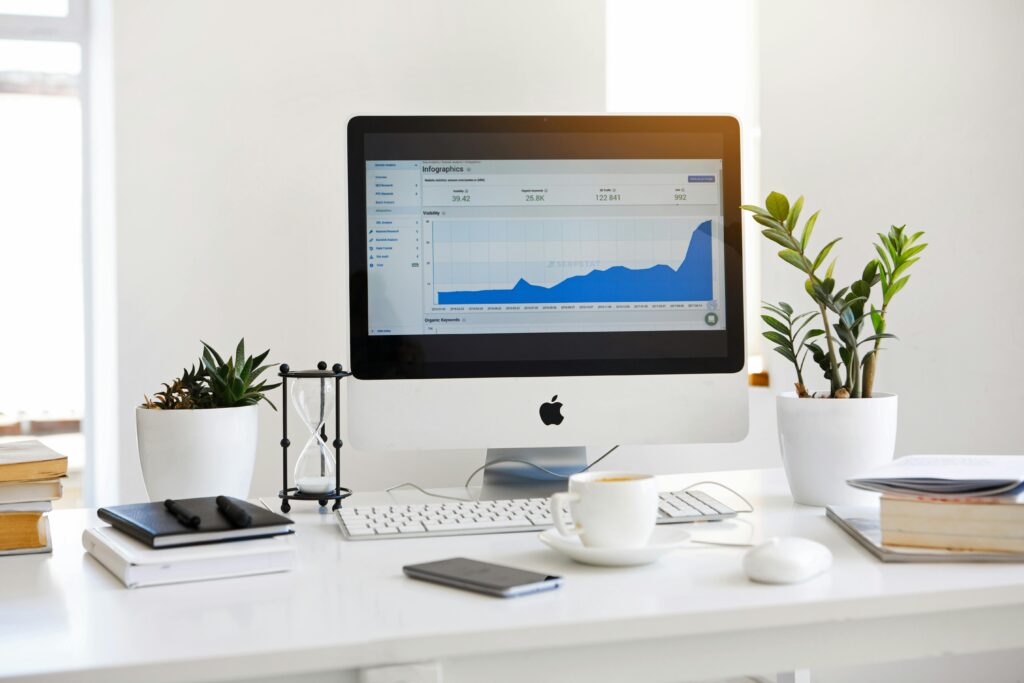 Computer on a desk showing a chart with an upward trend on the screen.